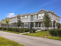 Two story homes at Summerwell Avian Pointe in Apopka, FL, featuring a grey exterior and grassy lawn.