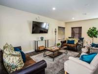 clubhouse lounge area with couches and arm chairs and tv at the cove apartments
