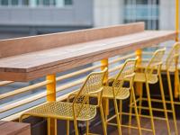bar with yellow bar chairs at oro apartments rooftop