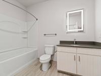 Bathroom with tub and backlit mirror vanity