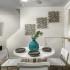 Dining area with white round table, white chairs, and breakfast bar. TV mounted next to stairs in the background