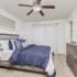 Carpeted living room with a large mirror, dresser, end tables, ceiling fan, and sliding doors leading outside.