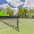 Close up of community tennis court with a bright green wall on the left side.