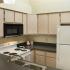 Looking into kitchen through counter space.  Kitchen has beige cabinets with white appliances.