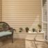 Screened patio with tile floor and wicker chair.  Small plants sitting on top of a built in bench along the wall.