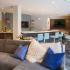Community clubhouse with sectional couch, pillows, bar with bar stools, wall mounted televisions on back wall.