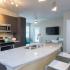 Kitchen area with wood tiled floors, stainless steel appliances, dark cabinets, modern lighting.