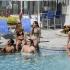 Community pool shot with seven young people in bathing suites, talking.