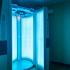 Community tanning booth, turned on.  Blue light emitting from the open doors.