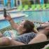 Young couple swinging on hammock next to pool.