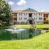 Lexington Crossing pond with fountain and grassy area, building exterior