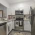 Kitchen with quartz countertops, hardwood floors, white cabinets, stainless steel appliances, and a passthrough