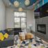 Community clubhouse area with a wall mounted TV, large windows, area rug, bar height dining set, fireplace, and a large couch.