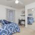 Carpeted bedroom with mirrors, closet, bed, desk. window, and ceiling fan.