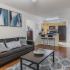 Living room with hardwood floors, kitchen passthrough, leather style couches, wall art, and access to private bedrooms.