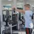 A young adult male wearing a blue shirt using resistance bands at the community gym.