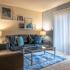 Carpeted living room with closed blinds, wall art, coffee table, two couches, and an end table with a lamp.