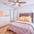 Carpeted bedroom with white walls, large windows, and white bedding.