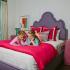 Swallowtail Flats at Old Town Bedroom: Purple Queen-sized bed, Two girls reading a book, Nightstand, Lamp, windows