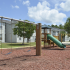 Overlook Gardens Exterior: Playground with swings, slide and jungle gym, surrounded by trees and apartments.