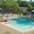 Club Hill Apartments Exterior: 2 level pool deck with sparkling swimming pool, lounge chairs, umbrella, and surrounding trees and building.