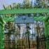 Club Hill Apartments Exterior: Entrance to Bark Park, with fencing, and many tall trees.