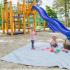 Club Hill Apartments Exterior: colorful playground with slides, and climbing, sand on the ground, 2 children play on a blanket.