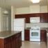 A kitchen with brown-red cabinets and white appliances. | Soaring Heights Communities Houses for Rent, Alamogordo, NM