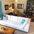 A brightly lit living room with a white couch and blue throw pillows in front of a few other chairs and a dark set of shelves in the back corner.  | Tierra Vista Communities Houses for rent, Los Angeles AFB