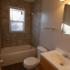 Newly remodeled bathroom with tile tub surround and vinyl wood flooring