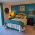 Calibre Bend Apartments unit bedroom: glass door to outdoor patio, bed, blue wall behind bed, decorations.