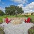 The Lodge at Woodlake apartments, exterior, stone fire pit, apartment exteriors, red lounge chairs, large grassy area and trees