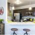 Side view of the kitchen with two bar stools against the half circular counter top. Two hanging lights
