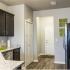 Kitchen view with light brown hardwood floors, two white doors against a light grey wall color