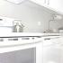 All white kitchen with upper and lower cabinets, with white dishwasher, and a white range.