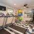 Two treadmills and weigh lifting station with tv and windows along the wall.