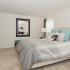 Furnished apartment bedroom with windows and plush carpeting