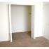 Carpeted model bedroom with large open closest at Oak Tree Apartments in Newark, DE.