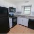 Kitchen with tile floor, white cabinets, and black appliances in apartment for rent in Reading, PA