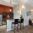 View into Kitchen with Bar Seating, Pendant Lights and Stainless Steel Side by Side Refrigerator