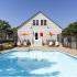 Pool with umbrella covered tables and seating with lounge chairs surrounding pool deck