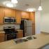 Kitchen bar view showing light maple cabinetry, light beige faux granite counters with sink and stainless appliances