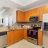 The Strand - Modern Kitchen With Appliances Suite, Spacious Wooden Cabinets, and Tile Flooring