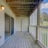 Large private balcony accessed through a sliding glass door that overlooks grass fields on the property.