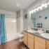 Bathroom featuring double vanity, combination tub/shower, with plenty of lighting at The Club at Chandler Crossings | Off-Campus Housing Near MSU.