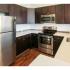 Homeroom Lofts Apartments, interior, kitchen, woof flooring, breakfast bar counter, gray doors, white walls, stainless steel appliances, refrigerator, microwave