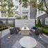 Outdoor lounge with cushioned patio furniture, a firepit and trees.