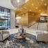 Resident clubhouse with 3 gray upholstered chairs, a coffee table, glass sliding doors to the exterior, and a staircase.