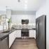 Kitchen with stainless steel appliances, white quartz cabinetry, granite countertops and dark wood-style floors.