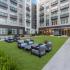 Outdoor courtyard with large grass area, 2 tables and upholstered patio-style chairs.